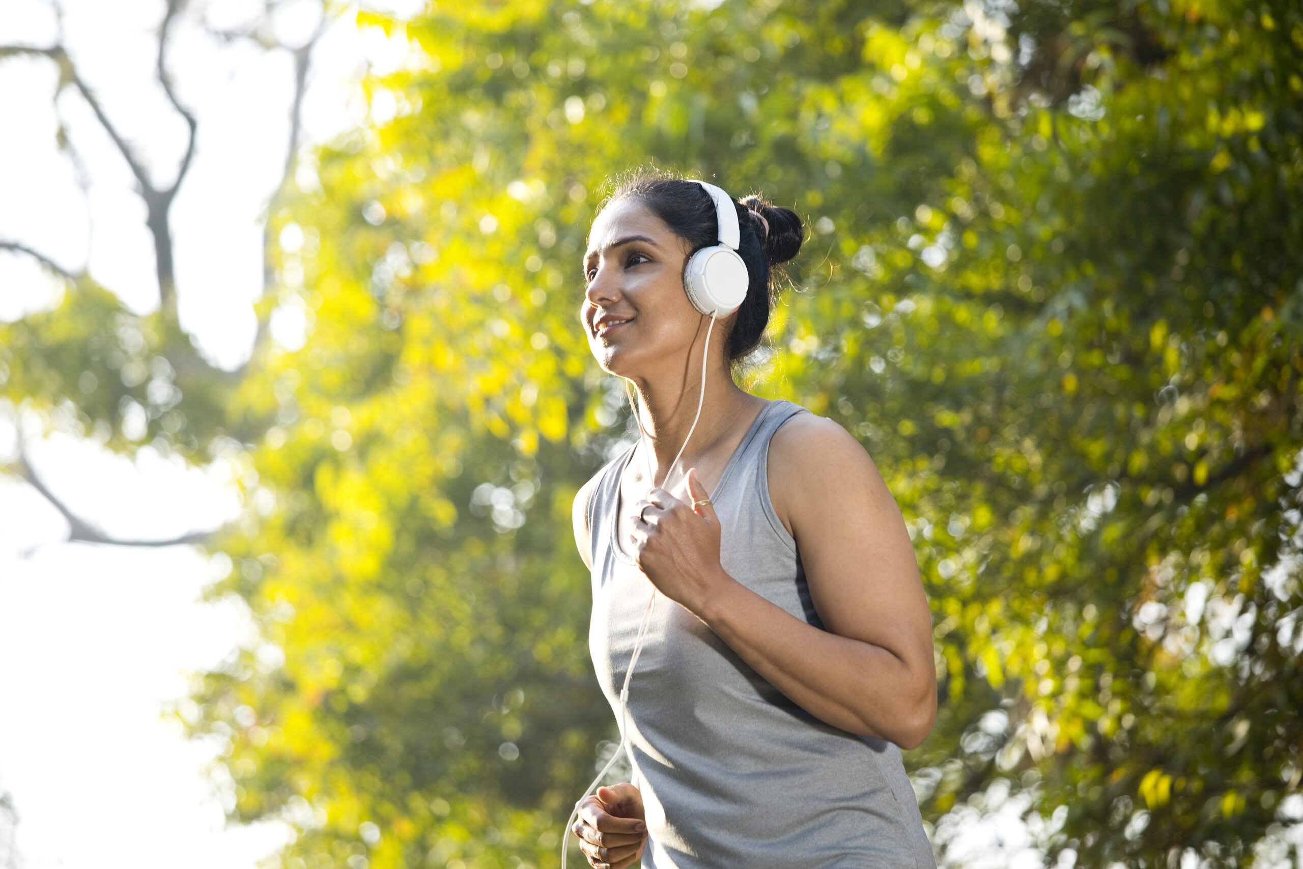 Fit woman in sportswear listening podcast on headphones while jogging at park